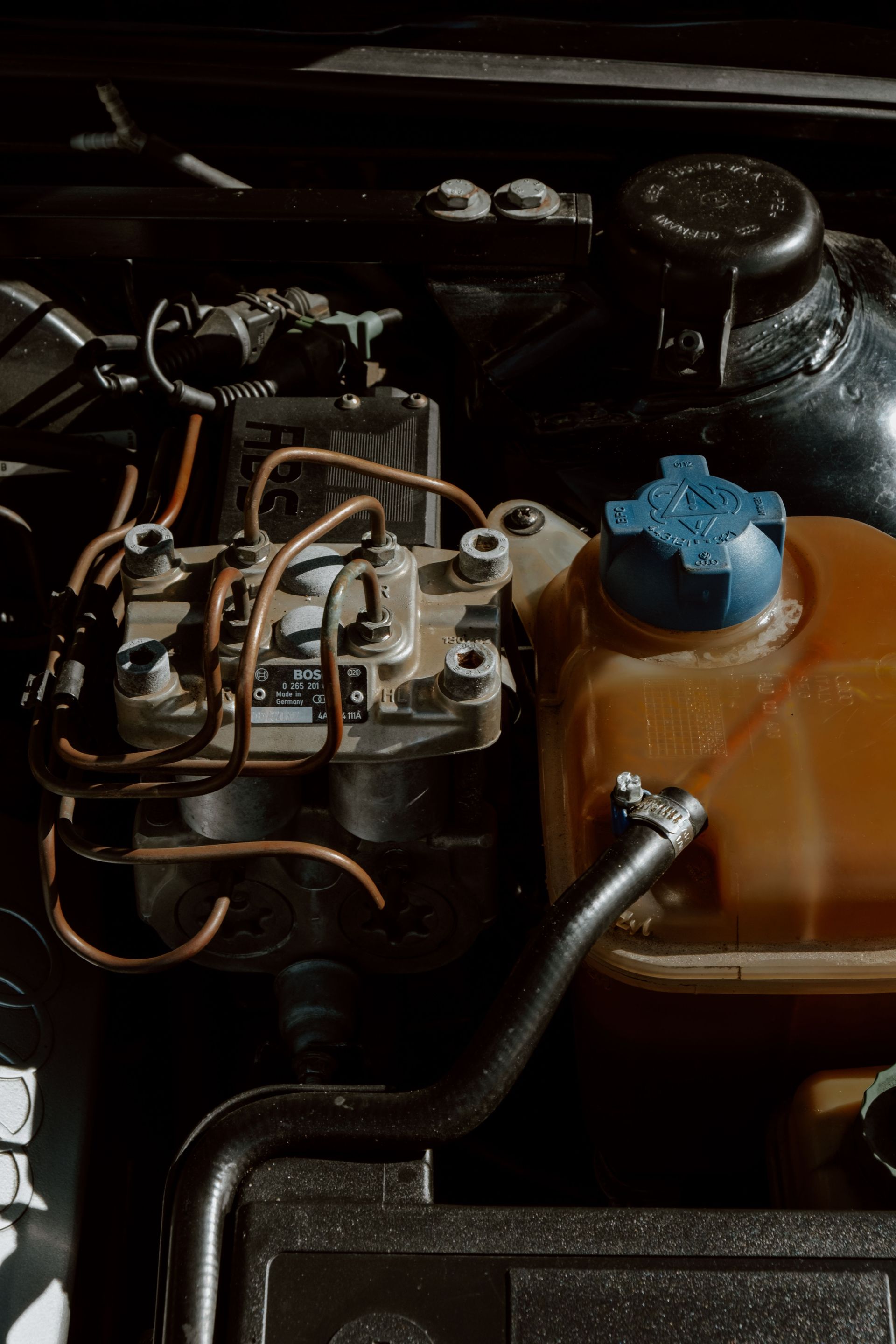 Detailed view of automobile engine parts and mechanisms with wiring and fluid container.